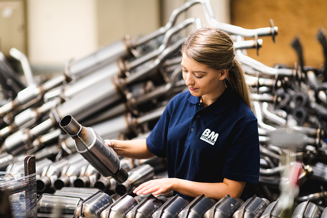 A woman is sorting through car parts in a manufacturing facility